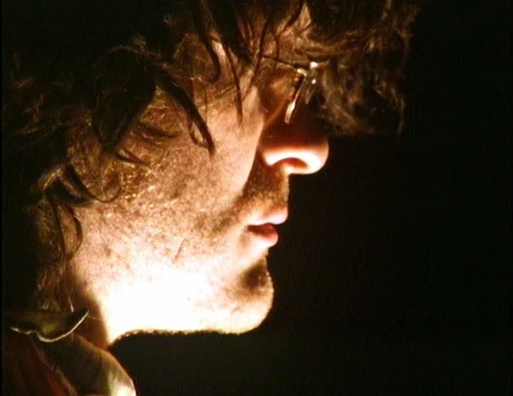 The Tempest (1979) movie still: closeup — A man's profile is illuminated by a sharp light in an otherwise dark environment. The subject looks toward…