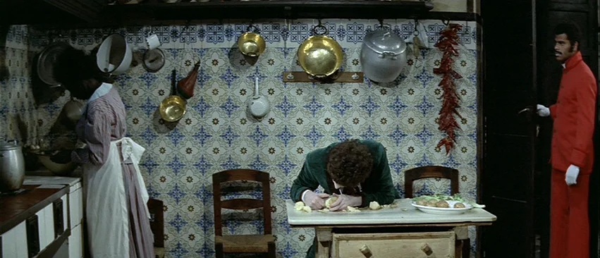 Whity (1971) movie still: wide — A rustic interior features intricate patterned tile walls and various hanging copper kitchenware. A person peels…