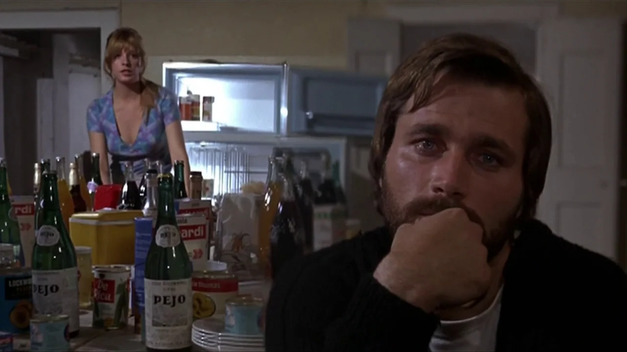 A Quiet Place In The Country (1968) movie still: medium — A cluttered table filled with glass bottles and food cans sits in the foreground. A man…