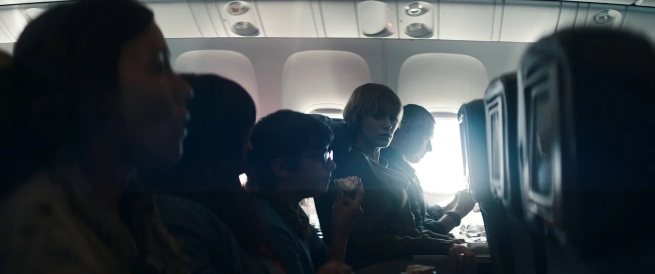 The Rhythm Section (2020) movie still: medium — A rows-based seating interior of a commercial airplane with passengers sitting near windows. The…