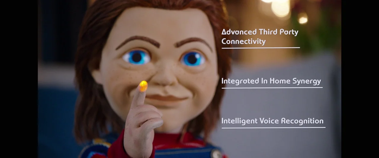 Child's Play (2019) movie still: closeup — A doll with red hair and blue eyes presents its glowing yellow index finger. Text overlays listing…