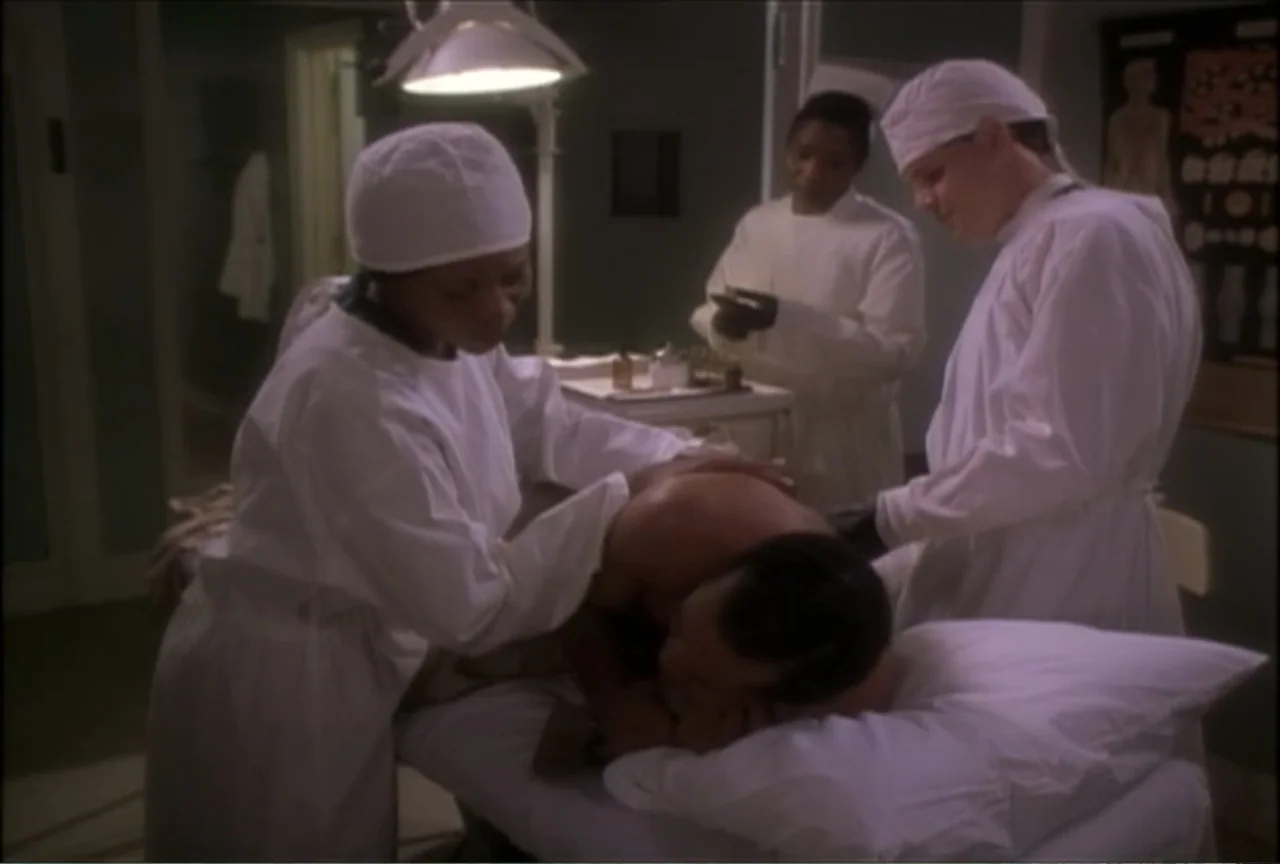 Miss Evers' Boys (1997) movie still: medium — A medical room features a central examination table surrounded by staff in clinical attire. Three…