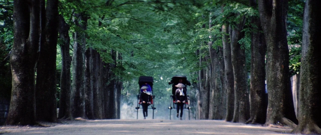 Lady Snowblood Song of Vengeance (1974) movie still: wide — A dirt path flanked by dense lines of mature trees forms a natural corridor. Two…