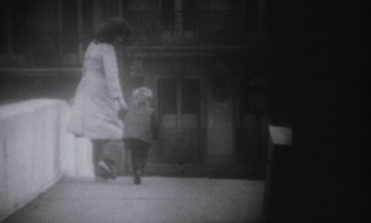 The Secret Son (1979) movie still: wide — A woman and a child walk across an illuminated bridge at night. The surrounding environment is dark and…