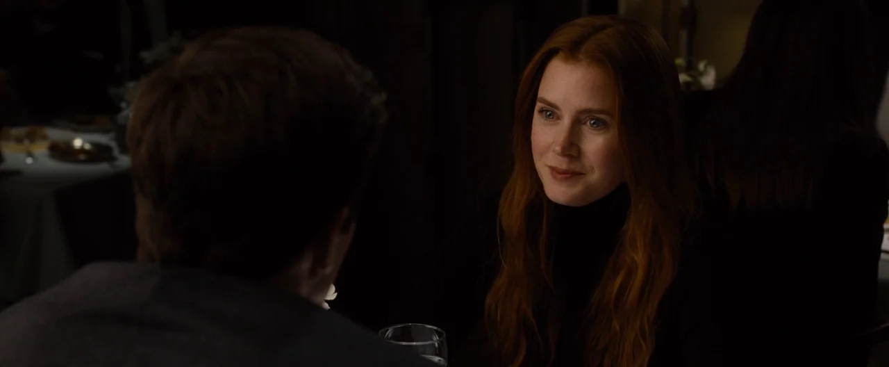 Nocturnal Animals (2016) movie still: medium — A dimly lit restaurant interior with dark surroundings and obscured tables in the background. A woman…