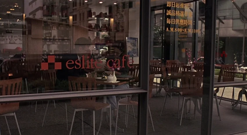 Yi-Yi (A One and A Two) (2000) movie still: wide — An Eslite cafe seen through a large glass storefront with multiple wooden tables inside. Text is…