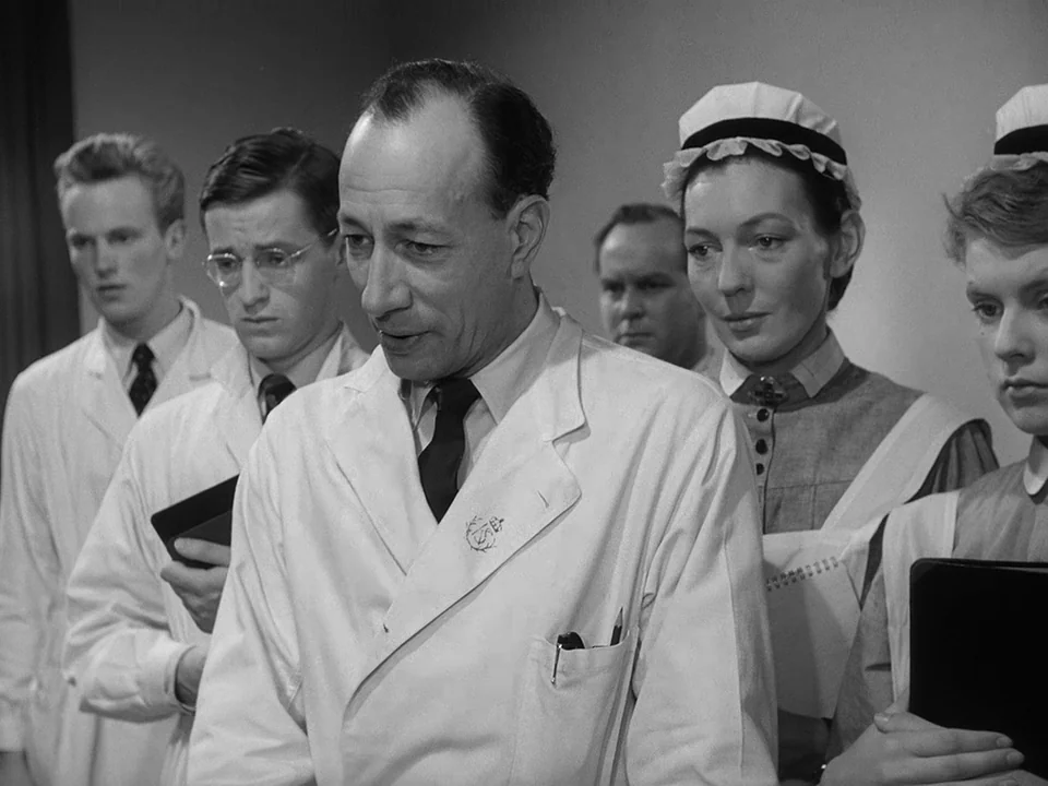 Brink of Life (1958) movie still: medium — A group of medical personnel in white coats and uniforms stand together indoors. The lead doctor…