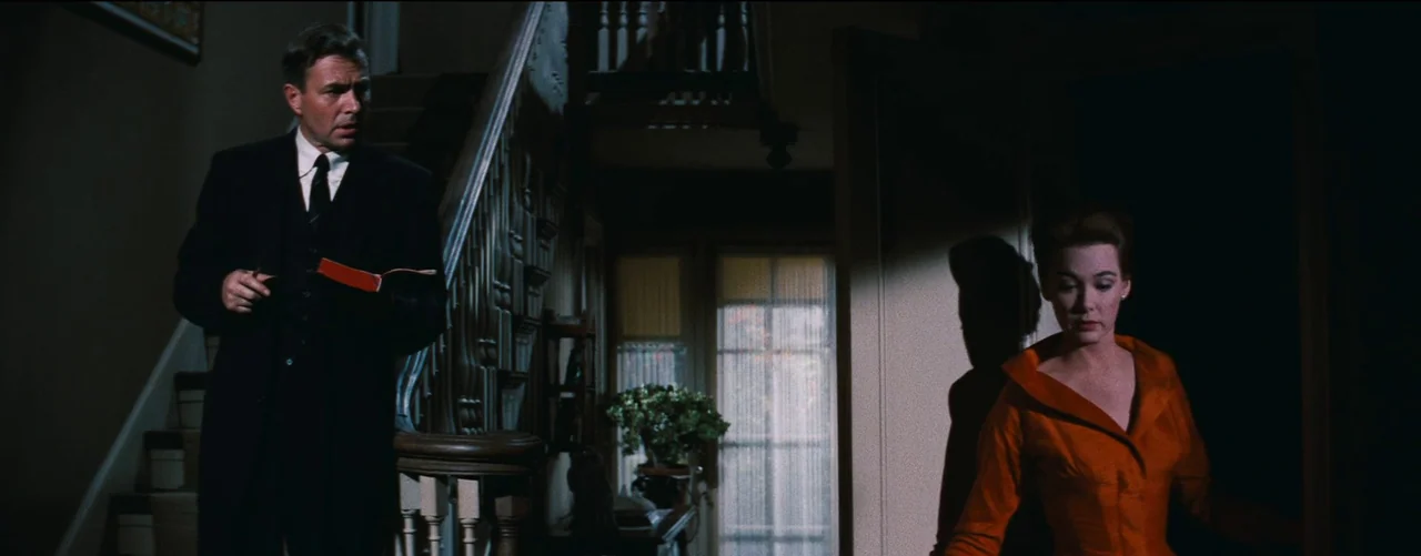 Bigger Than Life (1956) movie still: medium — An interior residential entrance features a wooden staircase and a back doorway with glass. A man…