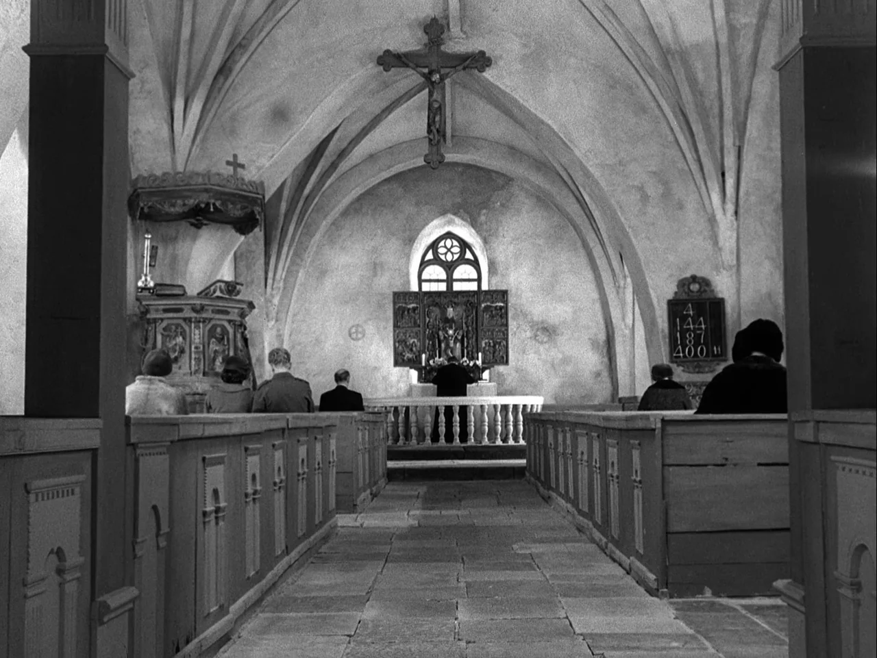 Winter Light (1963) movie still: wide — A stone church interior with vaulted ceilings and wooden pews arranged on either side. A priest stands at…
