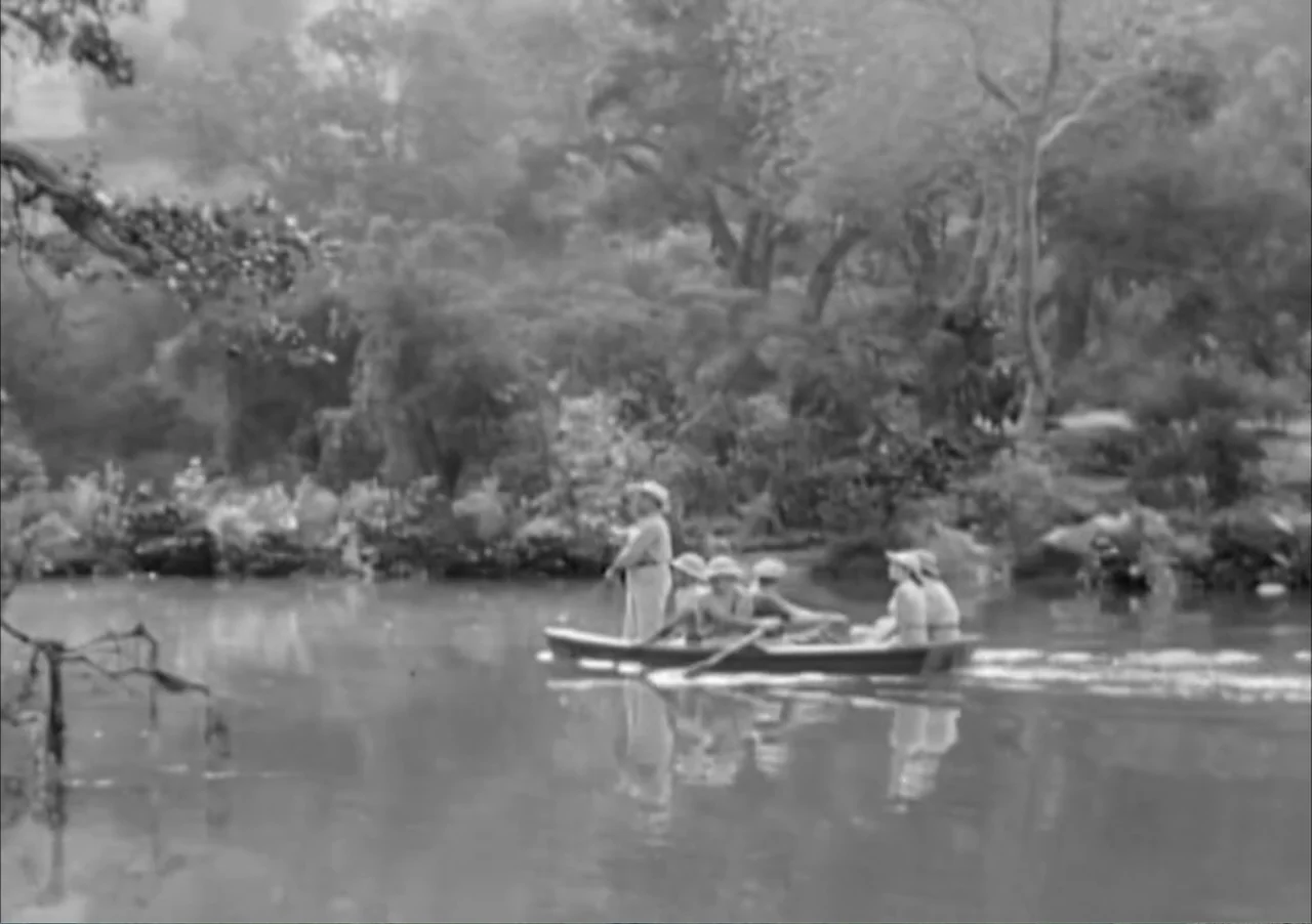 Creature from the Black Lagoon (1954) movie still: wide — A group of people navigate a small rowboat across a reflective, tree-lined lake. The…