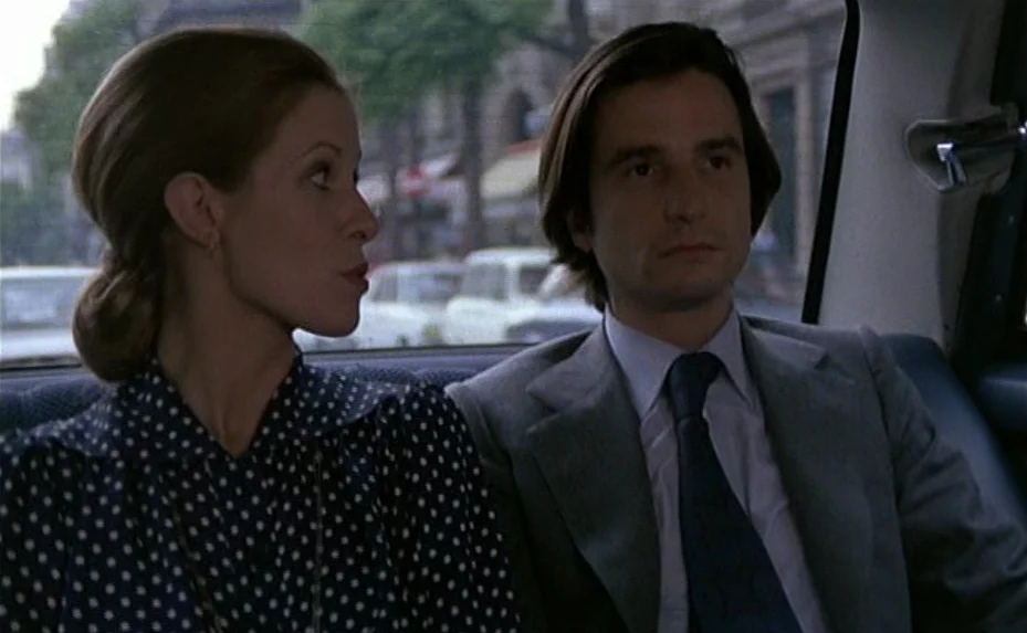 Love on the Run (1979) movie still: medium — A man and woman sit side by side in the back of a car. Buildings in a city street are visible through…