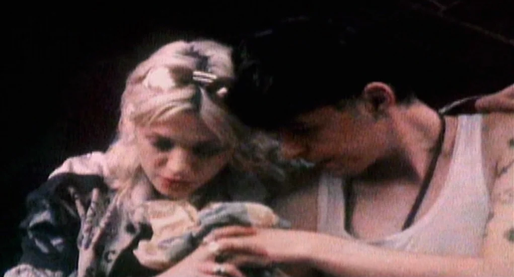 The Heart Is Deceitful Above All Things (2004) movie still: medium — A dimly lit room provides a dark, enclosed background for the two subjects. A…