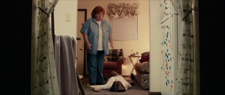 Bubble (2005) movie still: fullbody — A residential interior features a person standing over an individual prone on the floor. The space is…