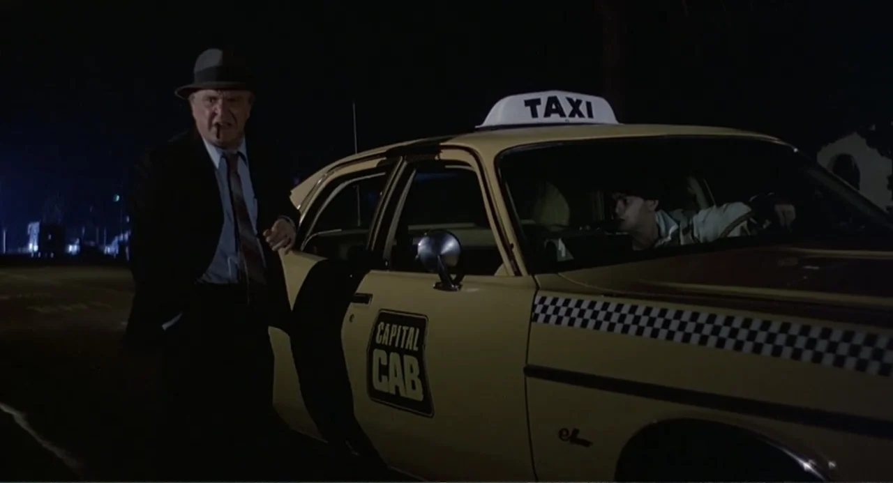 Death Wish II (1982) movie still: medium — A nighttime city street features a yellow taxi with a Capital Cab logo. An older man in a suit stands by…