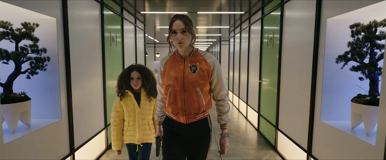 Gunpowder Milkshake (2021) movie still: medium — A long, clinical hallway features green-paneled doors and white walls with recessed bonsai…