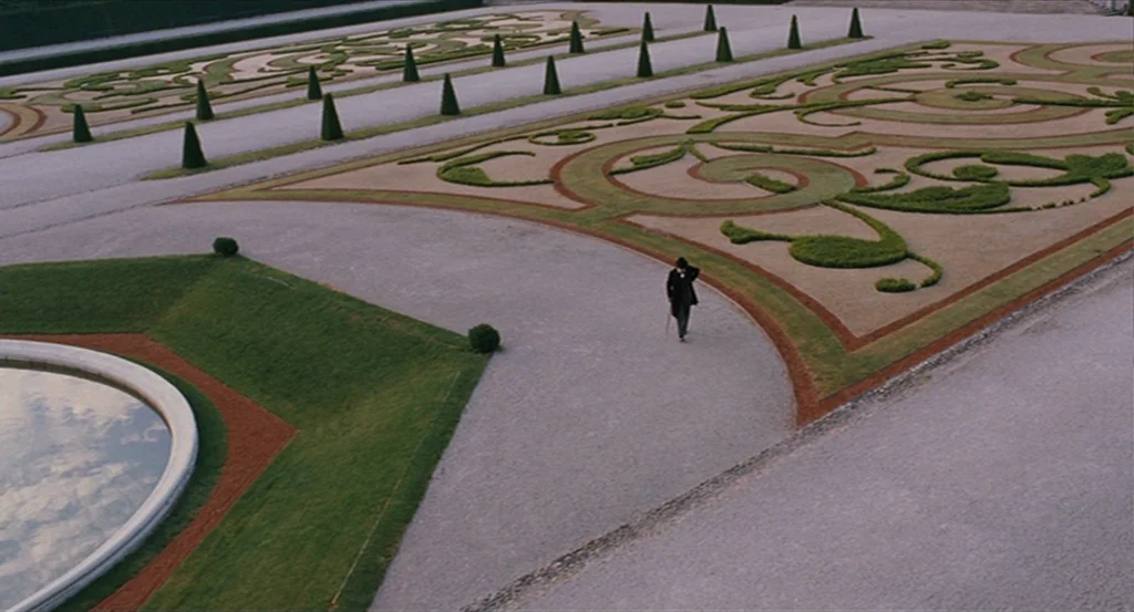 A Dangerous Method movie still: wide — A vast formal garden features symmetrical topiary designs set into patterned gravel beds. A lone man walks…