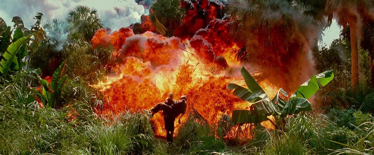 Forrest Gump (1994) movie still: wide — A dense tropical jungle clearing with lush green foliage and banana trees. A man carries another person away…