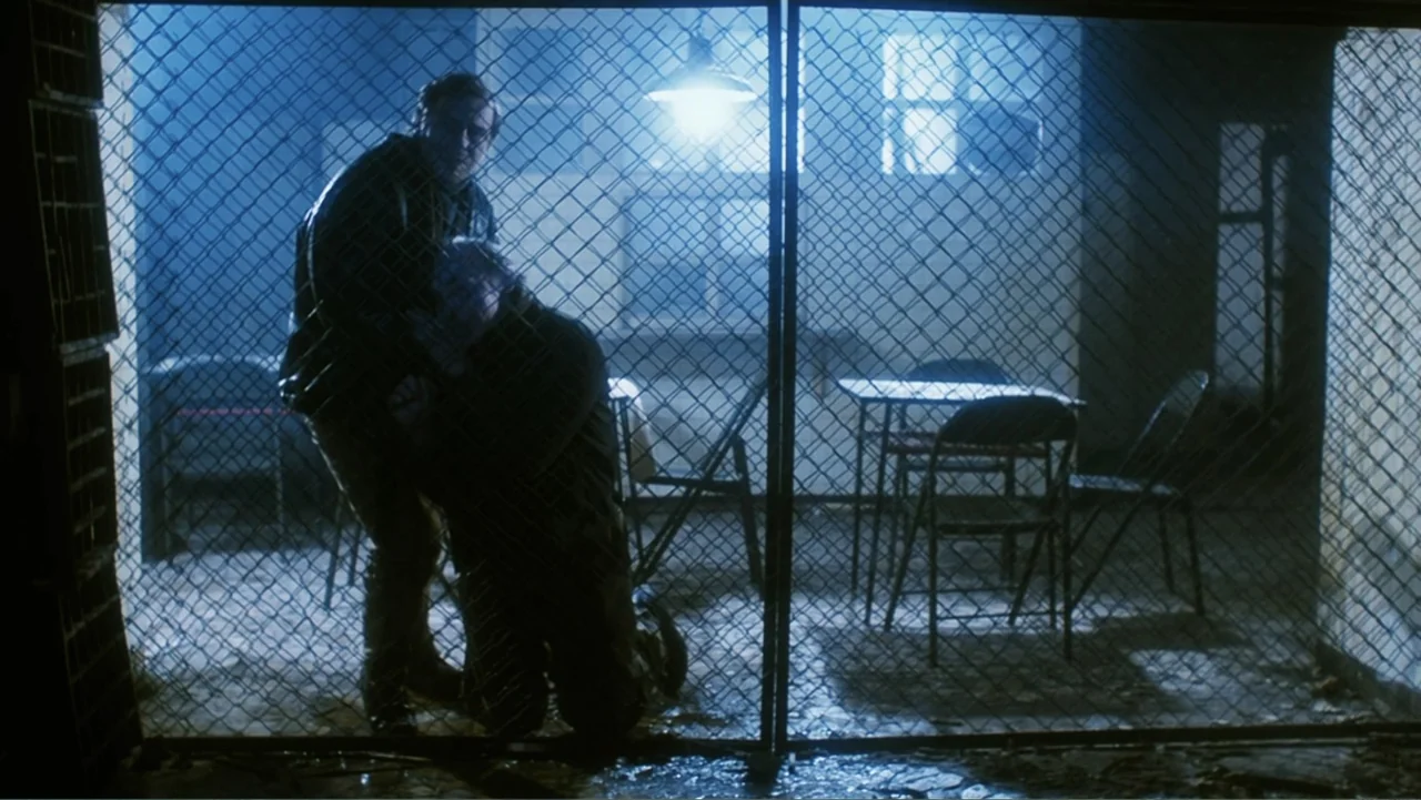 O-Bi, O-Ba: The End of Civilization (1985) movie still: medium — An interior space with wire mesh partitioning and sparse metal furniture in…