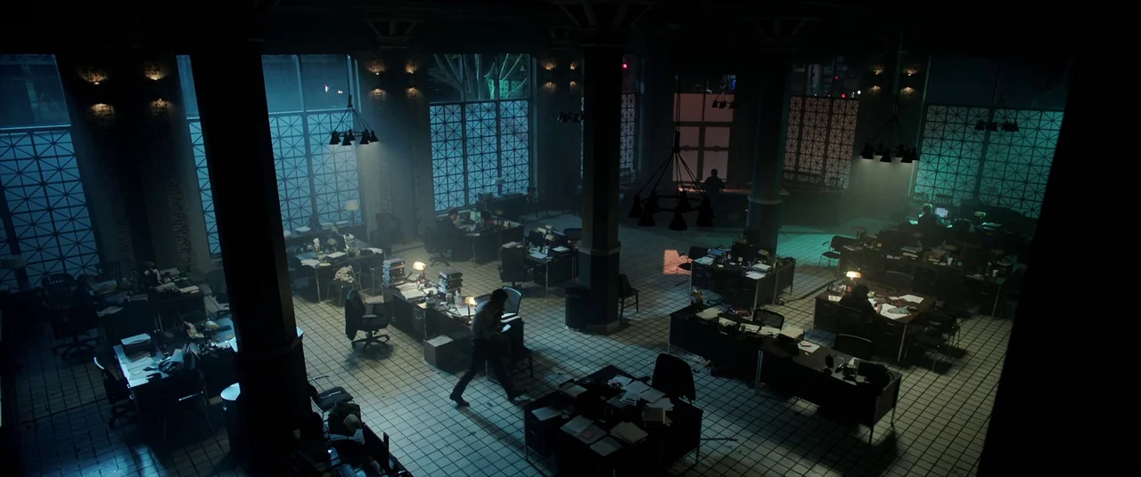 Malignant (2021) movie still: wide — A spacious, dimly lit open-plan office features tiled floors and large, grid-patterned windows. Rows of desks…