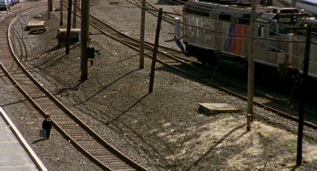 The Station Agent (2003) movie still: wide — An extensive network of iron railroad tracks traverses a wide gravel-covered industrial lot. A small…