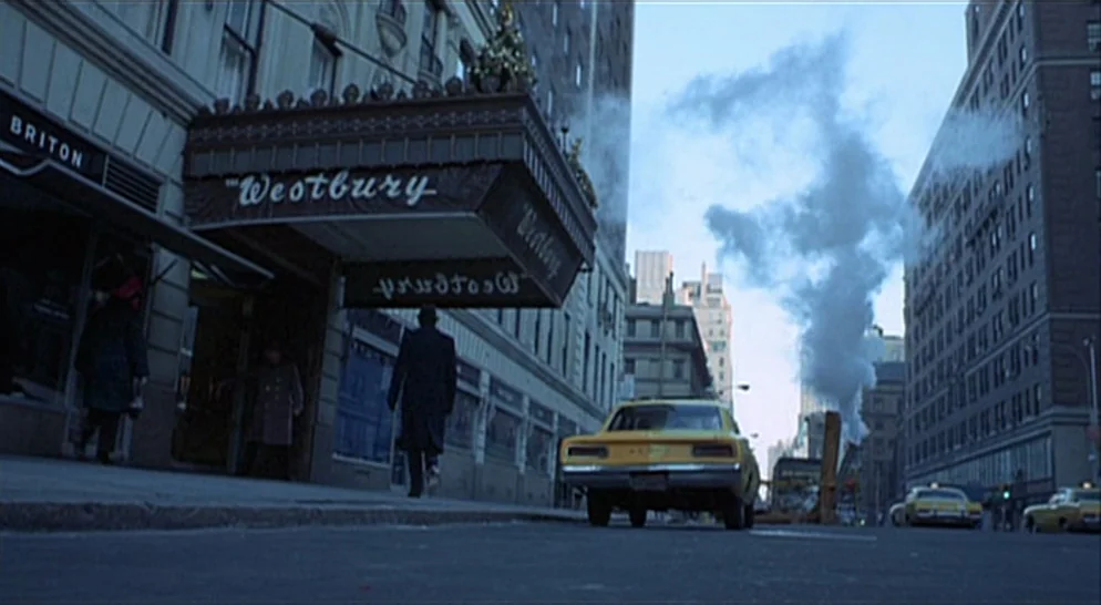 The French Connection (1971) movie still: wide — A city street in the 1970s features a hotel marquee and yellow taxis. Steam rises from a manhole in…