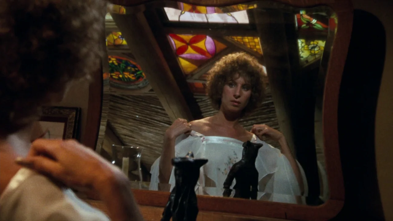 A Star Is Born (1976) movie still: medium — An interior bedroom features a wooden vanity mirror reflecting a woman and stained glass. The subject…