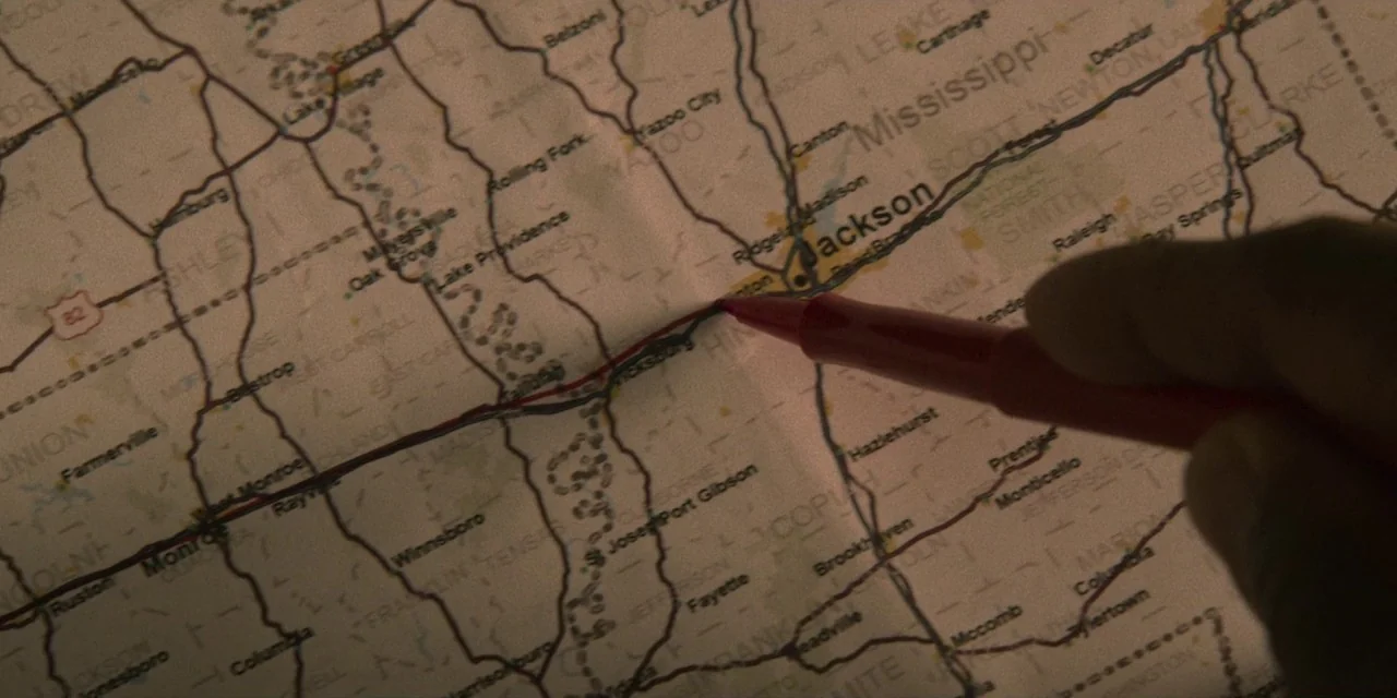 Dolemite Is My Name movie still: closeup — A close-up view shows a paper road map of Mississippi with printed highways. A hand holds a red felt-tip…