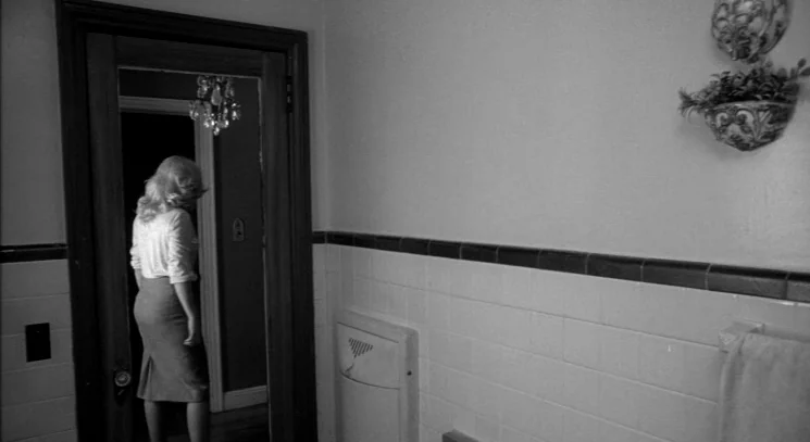 Raging Bull (1980) movie still: medium — A tiled bathroom with a dark door frame and a decorative wall planter. A woman with blonde hair stands in…