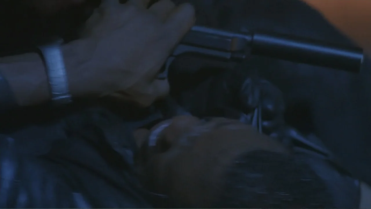 The Art of War (2000) movie still: closeup — A dark, dimly lit interior space with shadows obscuring most architectural details. A person in black…