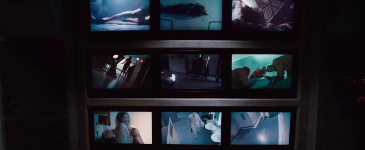 The Cabin In The Woods (2012) movie still: wide — A dark security control room features a grid of multiple glowing computer monitors. Each small…