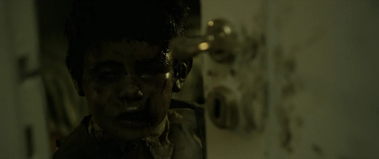 Terrified (2017) movie still: closeup — A dimly lit room threshold with a child's face partially visible in the frame. The child emerges from behind…