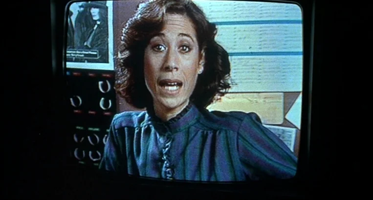 Videodrome (1983) movie still: medium — A woman appears on a television screen in a professional studio setting. She talks toward the lens while a…