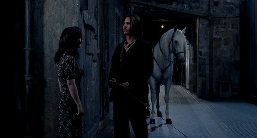 The Man Who Cried (2000) movie still: medium — A dark, narrow stone passageway provides the setting for a quiet interaction at night. A man in a…