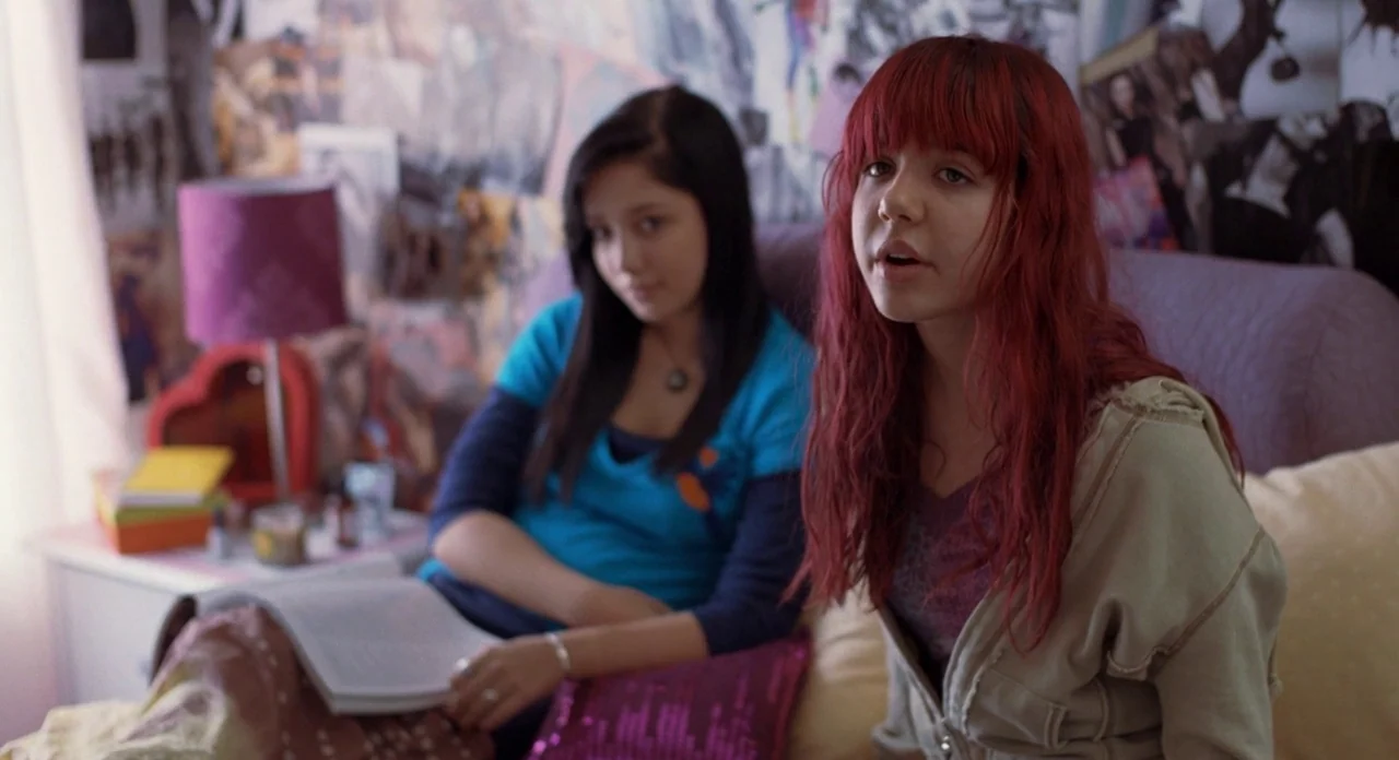 Boyhood (2014) movie still: medium — A teenager's room features walls covered with various photos and posters. Two young women sit on a bed with a…