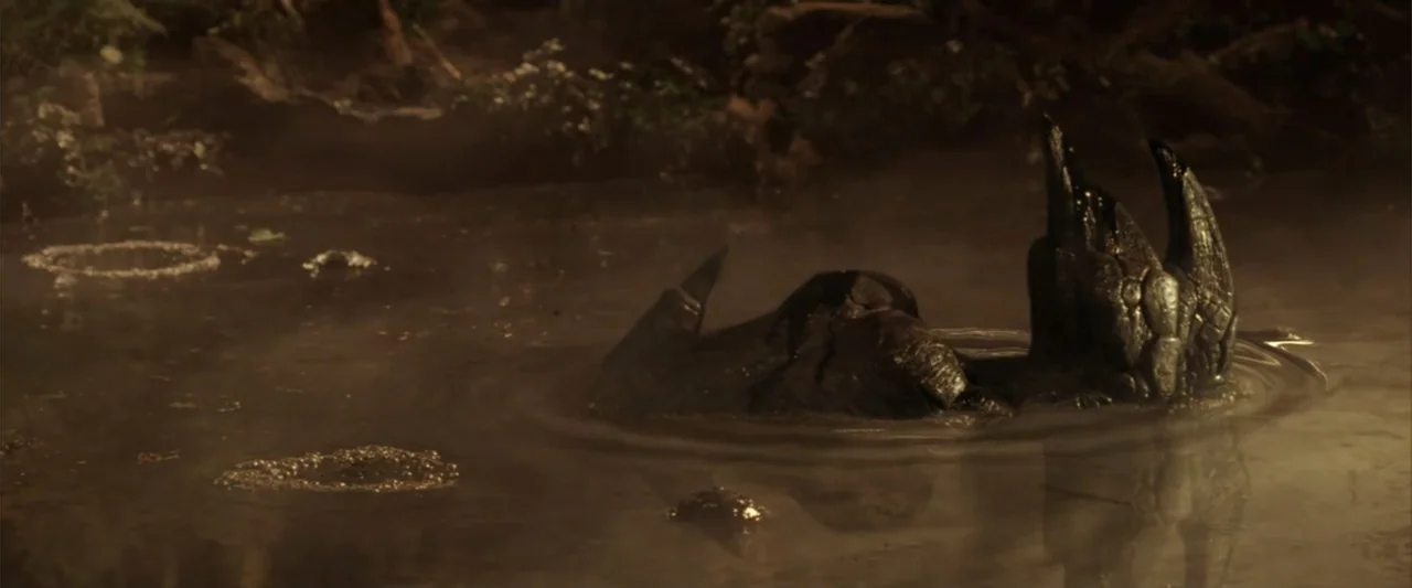 A Sound of Thunder (2005) movie still: medium — A murky, fog-filled swamp pool contains stagnant dark water and surrounding muddy terrain. A jagged,…
