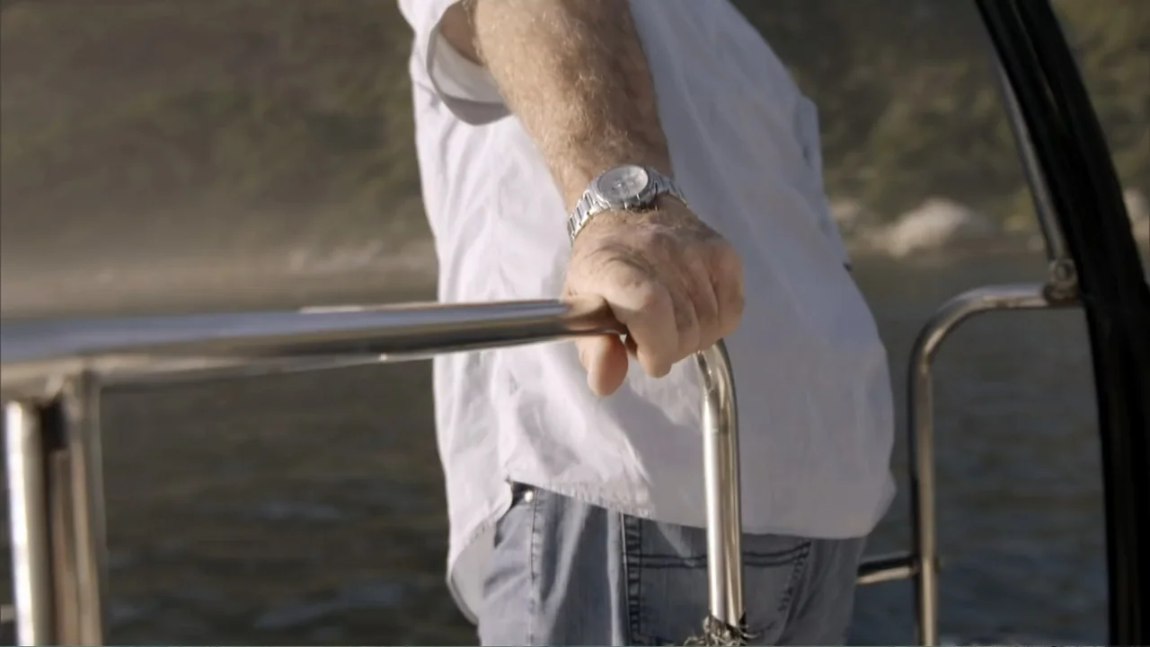 Megalodon: The Monster Shark Lives (2013) movie still: medium — A man stands on the deck of a boat with the ocean visible behind. The man grips the…