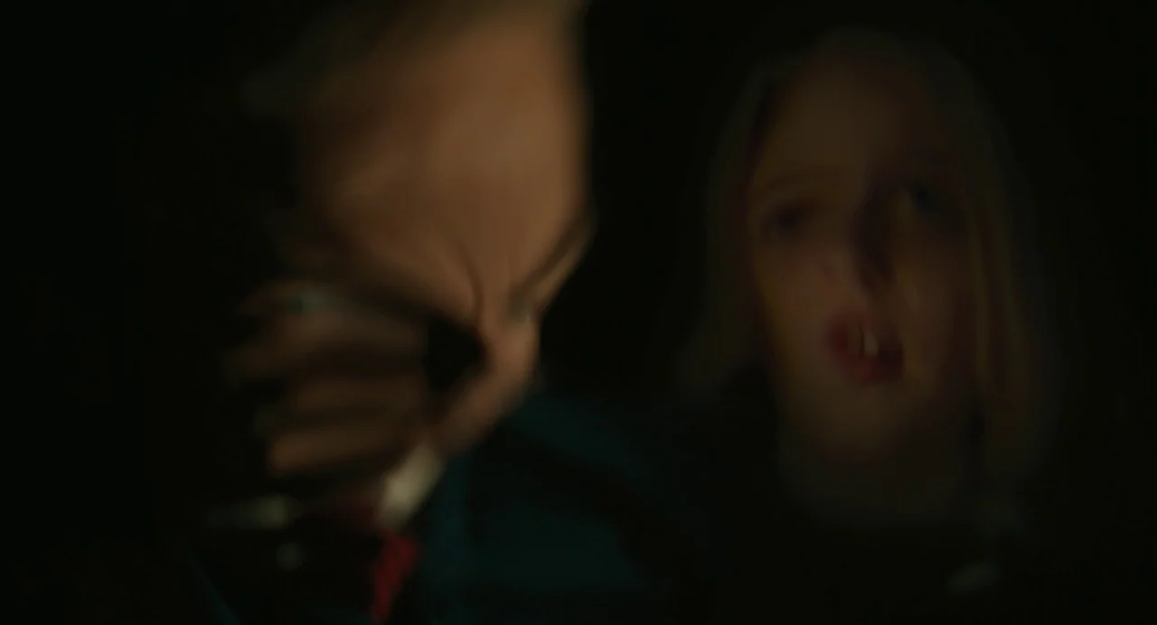 A Haunting In Venice (2023) movie still: closeup — A dark, cramped interior of a vehicle at night. A young child with blonde hair stares into the…