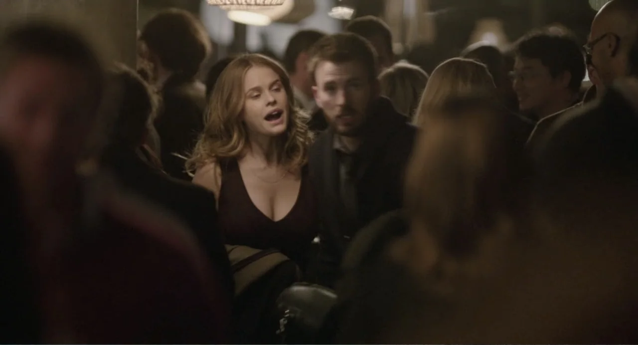 Before We Go (2014) movie still: medium — A crowded interior event space features dark walls and dimly lit surroundings. A woman and a man in…