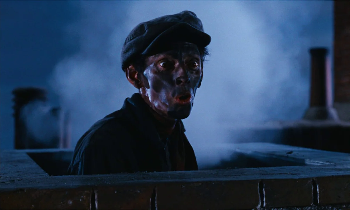 Mary Poppins (1964) movie still: medium — A man emerges from a dark rectangular masonry opening on a flat roof. Thick white smoke billows around the…