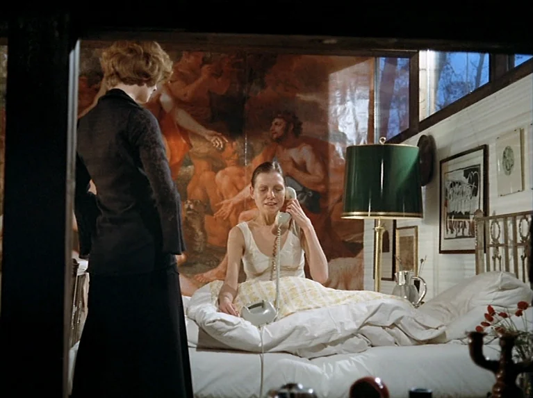 The Bitter Tears Of Petra Von Kant (1972) movie still: medium — A bedroom features a large classical-style mural behind a bed with white linens. A…