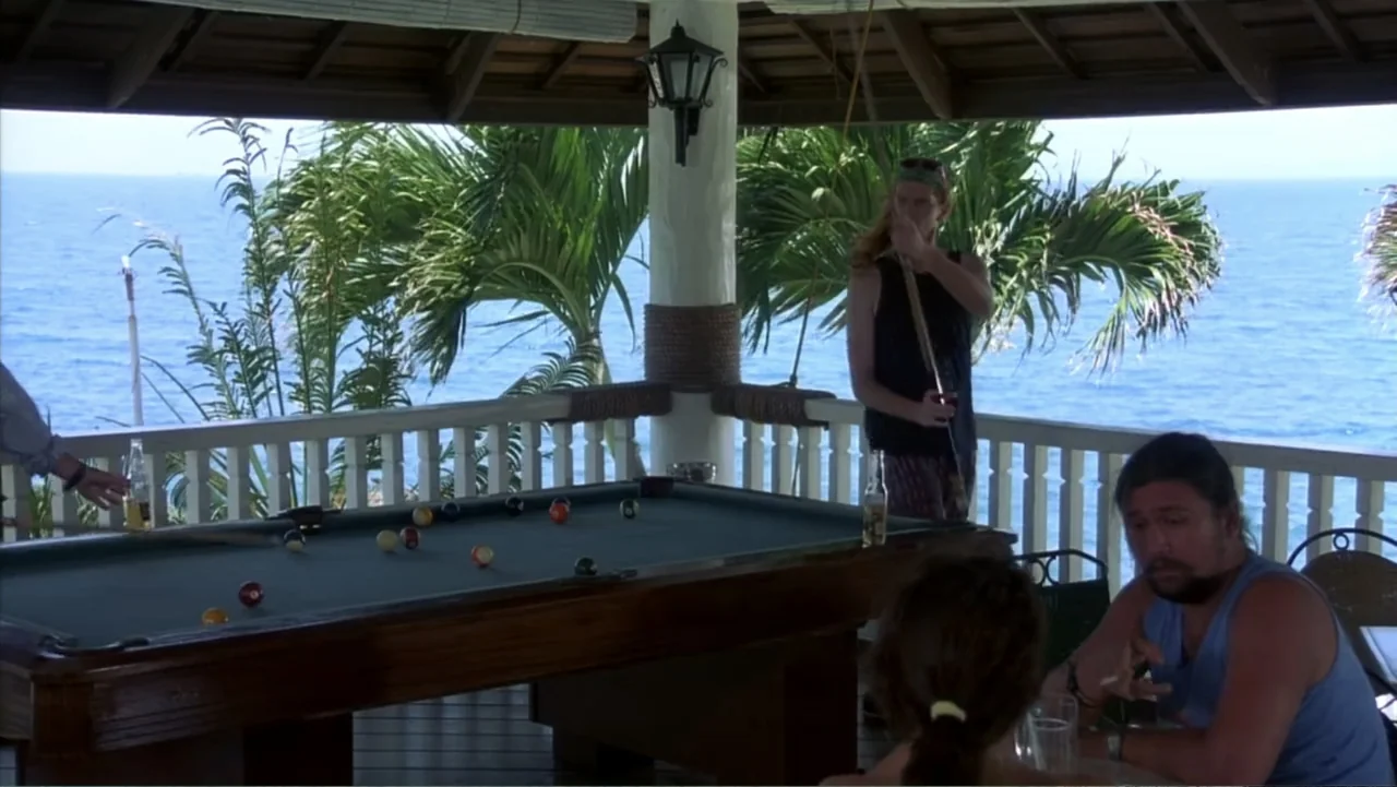 Behind Enemy Lines (2001) movie still: medium — An open-air seaside deck features a wooden billiard table under a roofed structure. Three people…