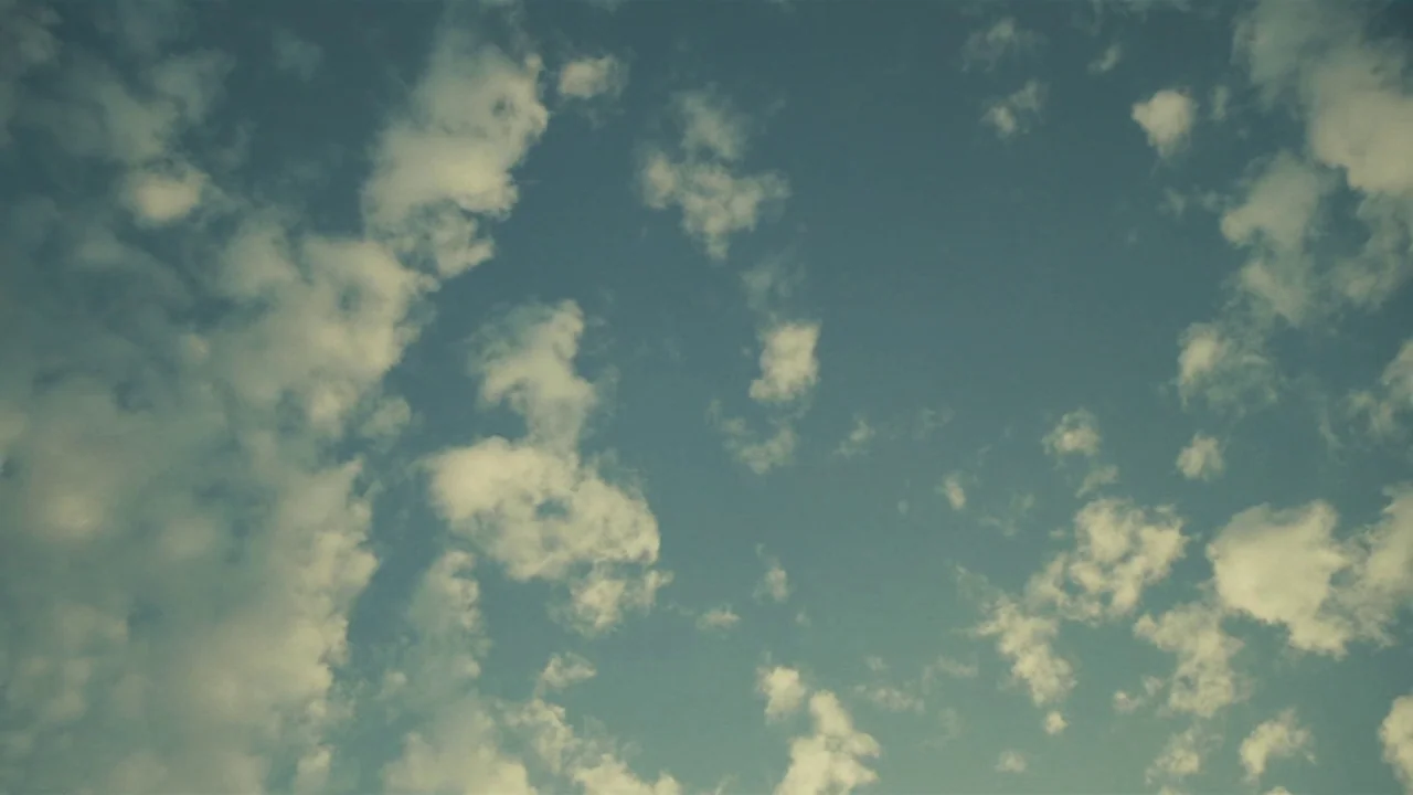 Amanda (2022) movie still: establishing — A vast expanse of sky is filled with scattered, light-colored cumulus clouds. The scene is dominated by…