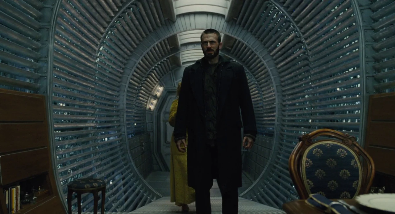 Snowpiercer (2013) movie still: fullbody — A long, cylindrical train car features curved metal ribs and recessed illumination. A man with a dark…