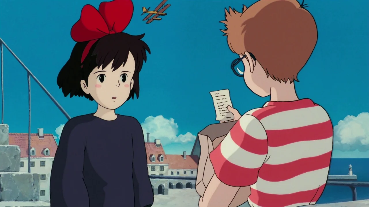 Kiki’s Delivery Service (1989) movie still: medium — A bright coastal town with stone architecture overlooks a blue sea under a clear sky. A boy in…
