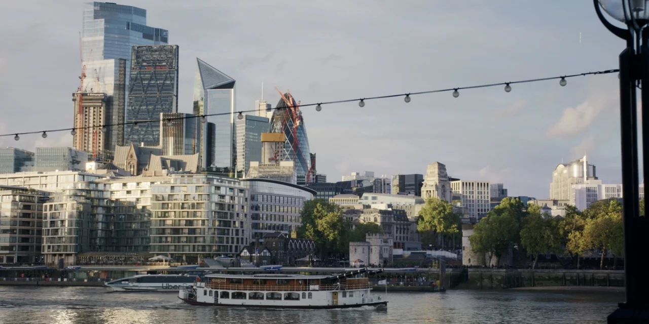 The People We Hate at the Wedding (2022) movie still: wide — The London skyline rises behind the River Thames with various modern glass skyscrapers…