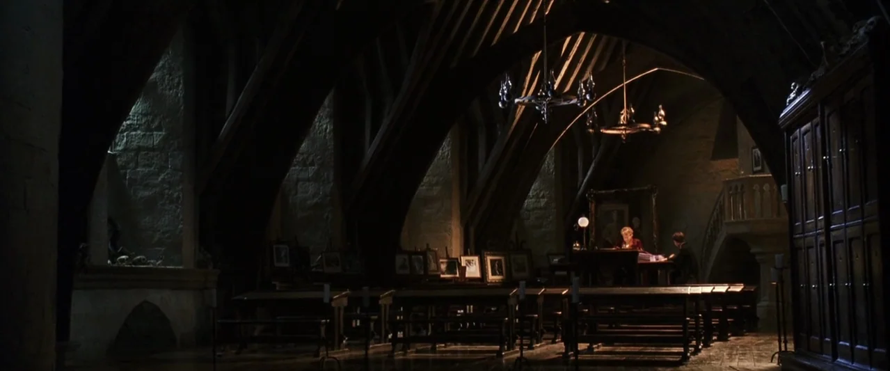 Harry Potter and the Chamber of Secrets (2002) movie still: wide — A spacious gothic room with arched stone beams, dark wooden benches, and pointed…