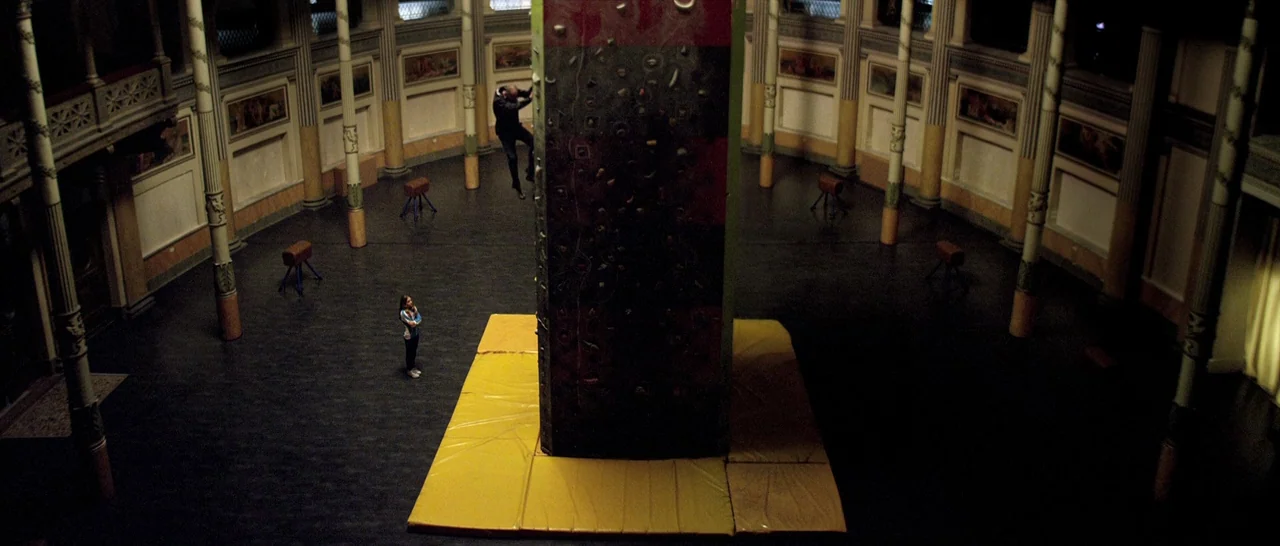 Youth (2015) movie still: wide — A spacious, circular hall features tall pillars and decorative wall panels surrounding a climbing structure. A man…