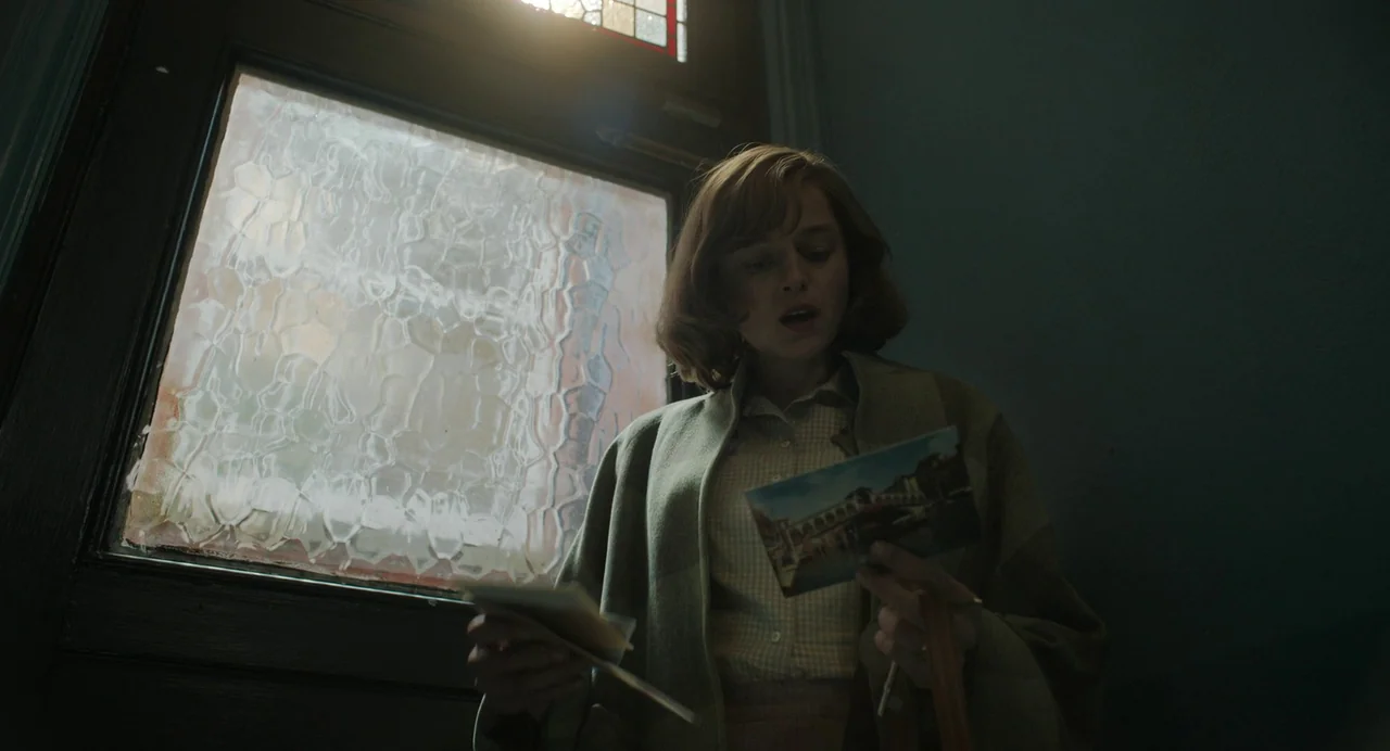 My Policeman (2022) movie still: medium — A dimly lit indoor space with a window featuring textured glass and stained glass detailing. A young woman…