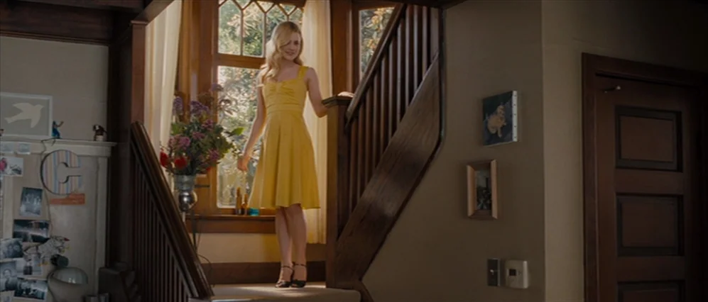 Drag Me to Hell (2009) movie still: fullbody — A wooden staircase landing features a window with white curtains and a floral arrangement. A young…
