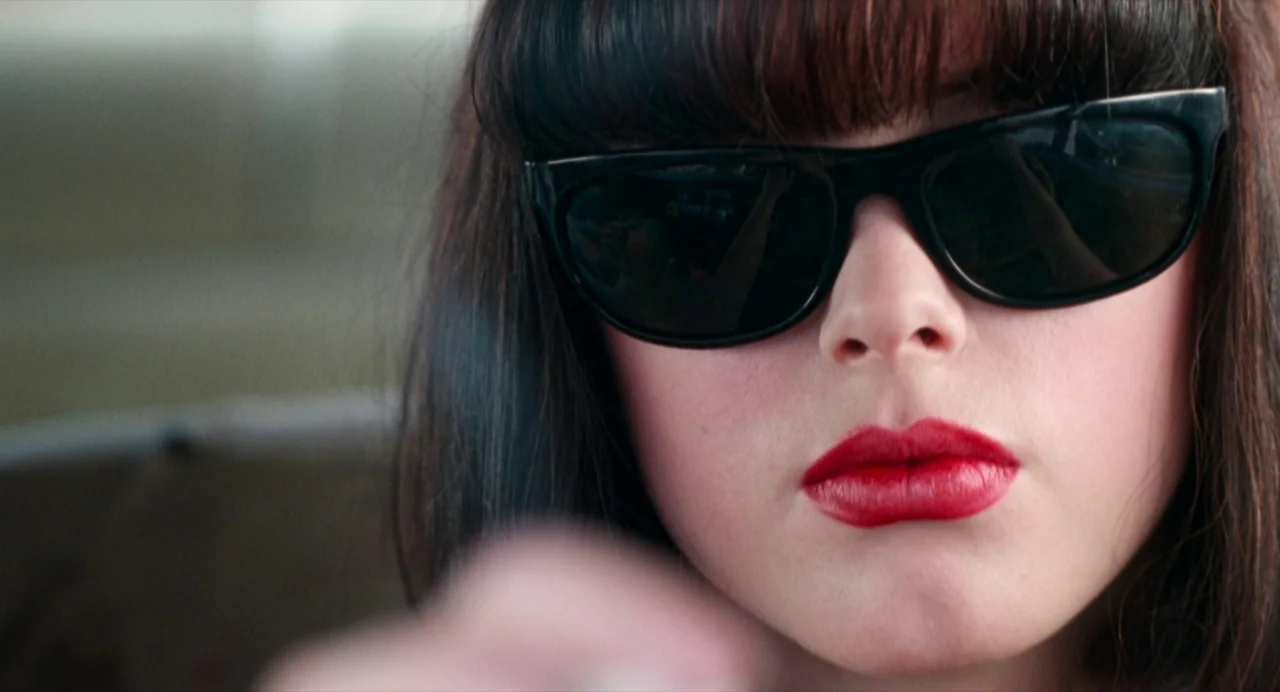 The Doom Generation (1995) movie still: closeup — The interior of a moving vehicle with light filtering through the windshield. A young woman with…